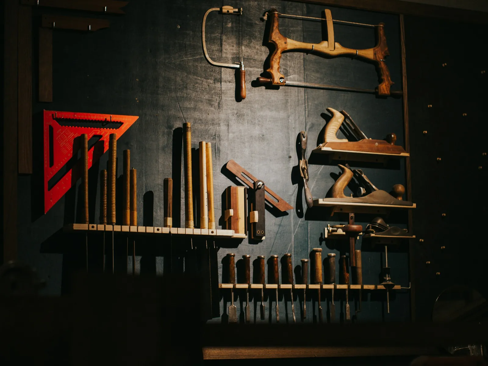 Werkzeug an einer dunklen Werkstattwand, als Bild für die Herkunft aus dem Handwerk